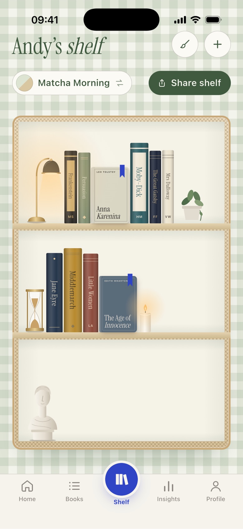 Readista shelf in the Matcha Morning theme, with books, a desk lamp, a plant, an hourglass and a candle